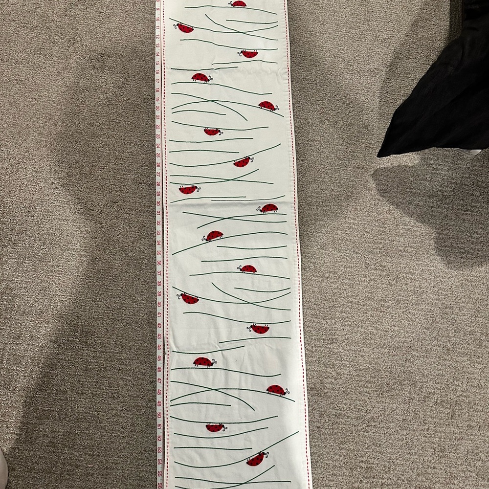White table runner with ladybug design also includes two place settings
